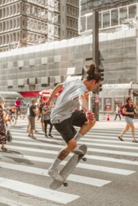 Skateboarder performing a trick on a busy city pedestrian crossing.