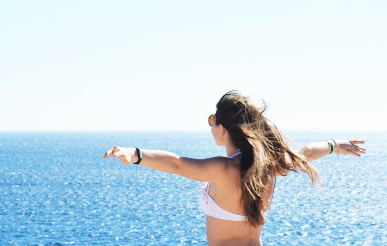 A woman in a bikini enjoying a sunny day by the sea with open arms in Sharm El Sheikh, Egypt.