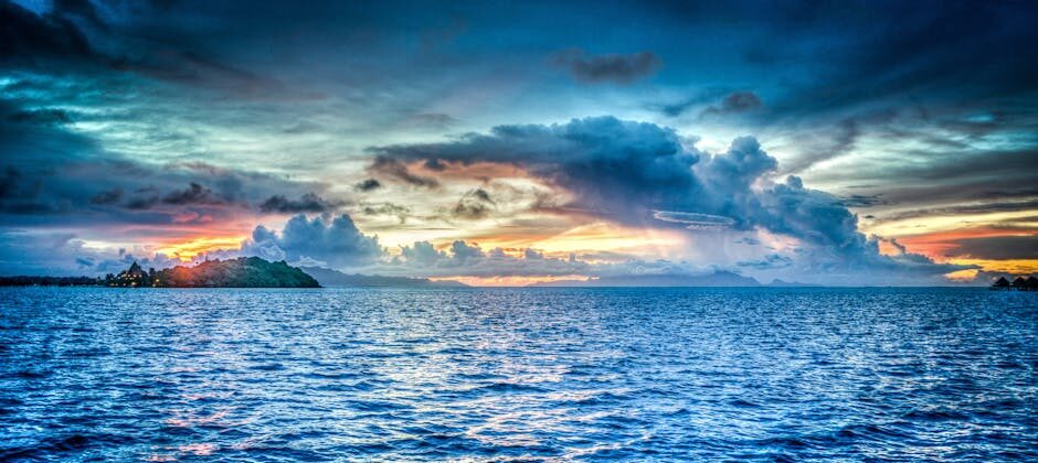 Vibrant sunset over tropical ocean with dramatic clouds and distant island.
