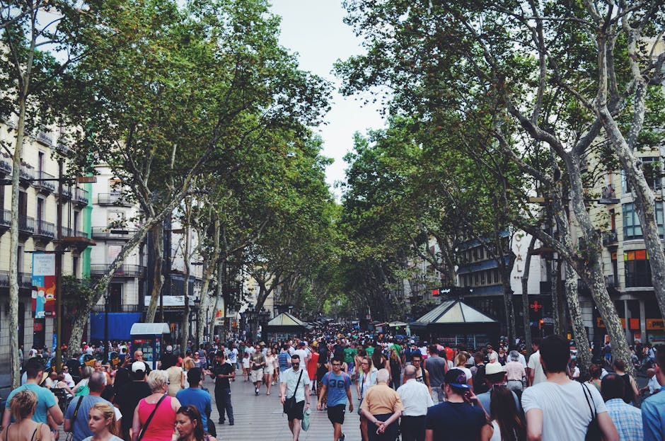 A vibrant street filled with people and trees, showcasing urban life in Barcelona.