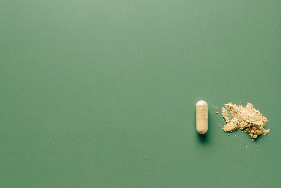 pexels-photo-7615560-7615560 Close-up of herbal supplement capsule and powder on a minimalist green surface.